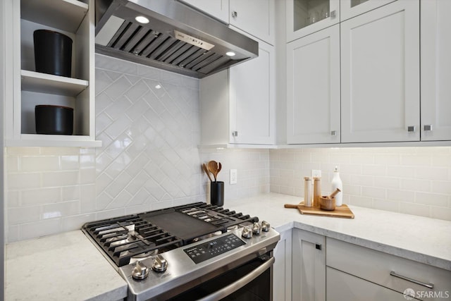 kitchen with white cabinets, glass insert cabinets, stainless steel gas stove, backsplash, and ventilation hood
