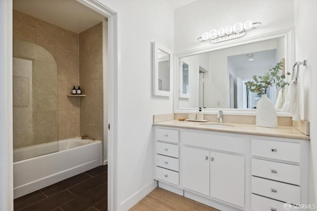 bathroom with baseboards, wood finished floors, vanity, and shower / bathtub combination
