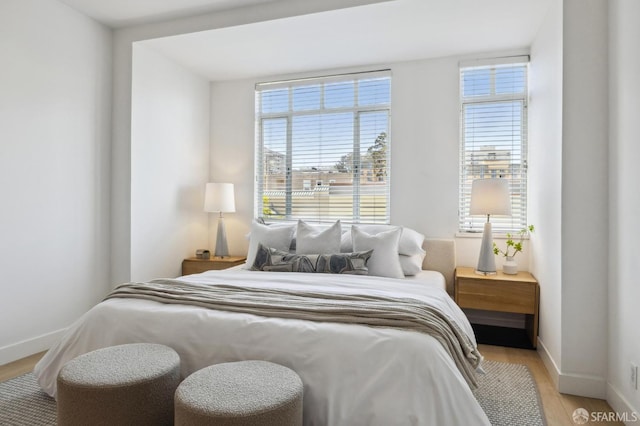 bedroom with wood finished floors, baseboards, and multiple windows