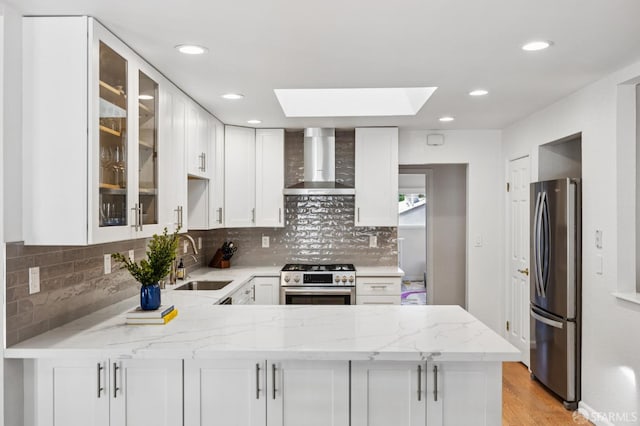 744 Crompton Rd, Redwood City, CA 94061 - kitchen with wall chimney exhaust hood, appliances with stainless steel finishes, a peninsula, a skylight, and light stone counters
