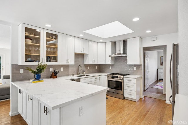 744 Crompton Rd, Redwood City, CA 94061 - kitchen featuring stainless steel appliances, wall chimney range hood, a skylight, a peninsula, and white cabinetry