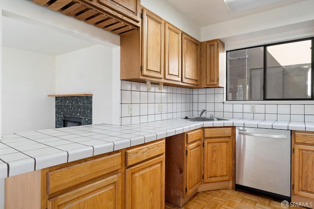 kitchen featuring light parquet flooring, sink, dishwasher, backsplash, and tile counters