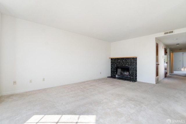 unfurnished living room with a tiled fireplace and light carpet