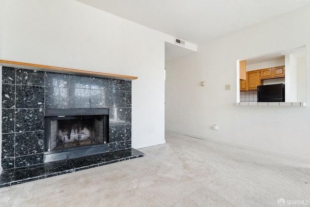 unfurnished living room with light colored carpet and a fireplace