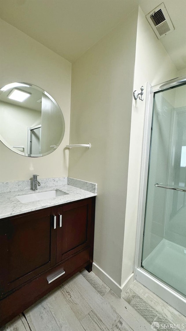 bathroom with vanity, hardwood / wood-style floors, and a shower with door