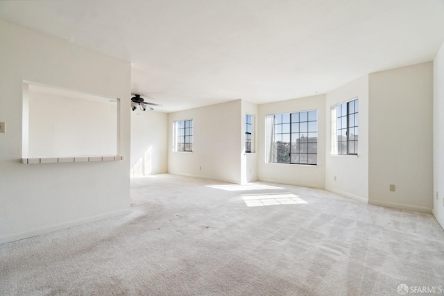 unfurnished room with light colored carpet, plenty of natural light, and ceiling fan