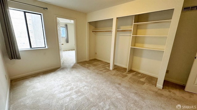 unfurnished bedroom with multiple closets and light carpet