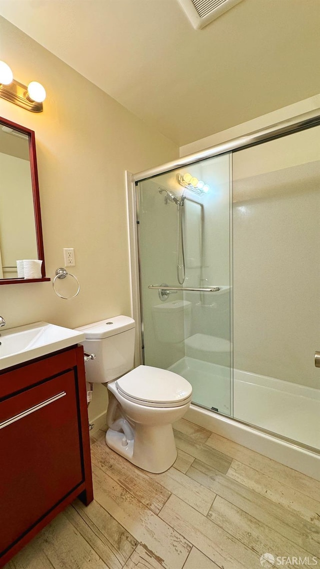 bathroom featuring vanity, toilet, hardwood / wood-style flooring, and an enclosed shower