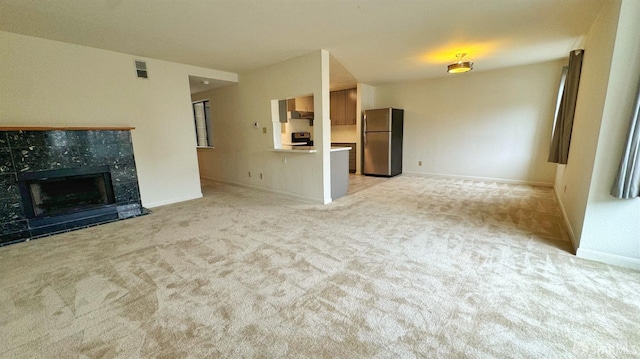 unfurnished living room with a fireplace and light colored carpet