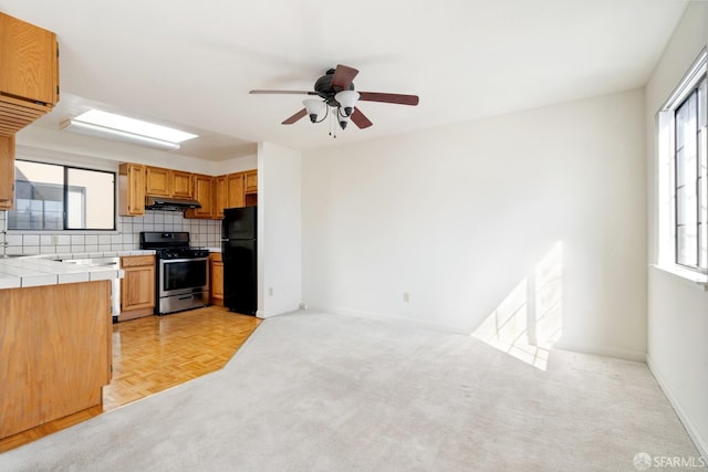 kitchen with tile countertops, plenty of natural light, stainless steel range, and black refrigerator