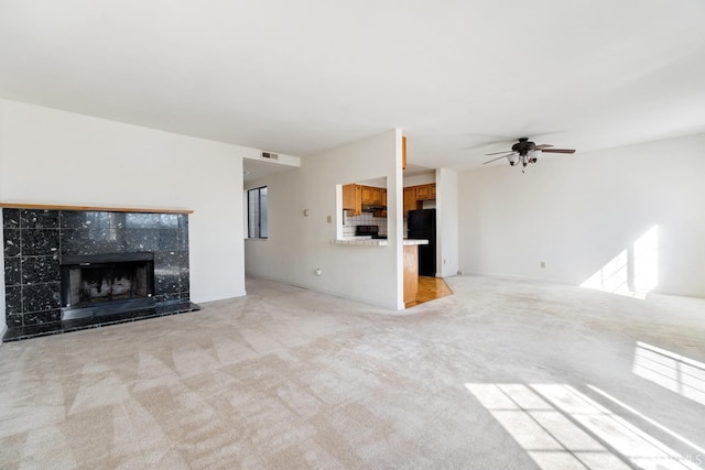 unfurnished living room with light colored carpet, a tile fireplace, and ceiling fan