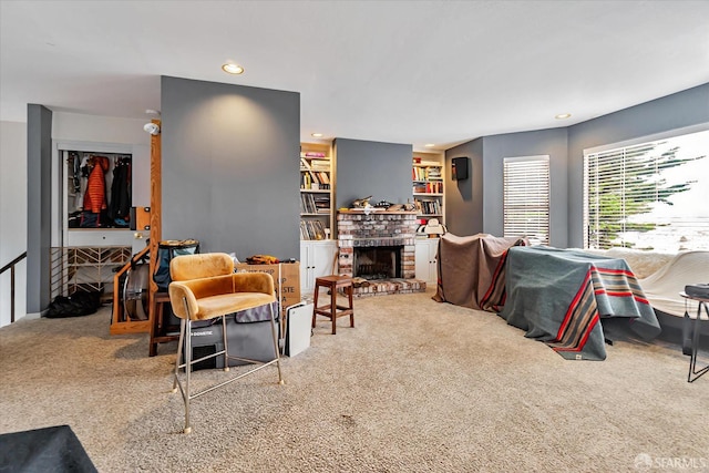 carpeted living room with built in shelves, a brick fireplace, and recessed lighting