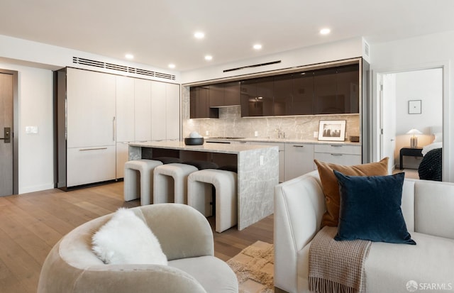 kitchen featuring light countertops, backsplash, a center island, light wood finished floors, and modern cabinets