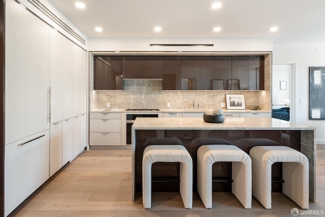 kitchen featuring a kitchen breakfast bar, light wood-type flooring, modern cabinets, and a center island