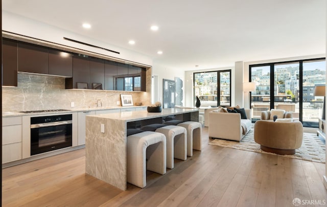 kitchen with tasteful backsplash, appliances with stainless steel finishes, white cabinetry, modern cabinets, and light wood-type flooring