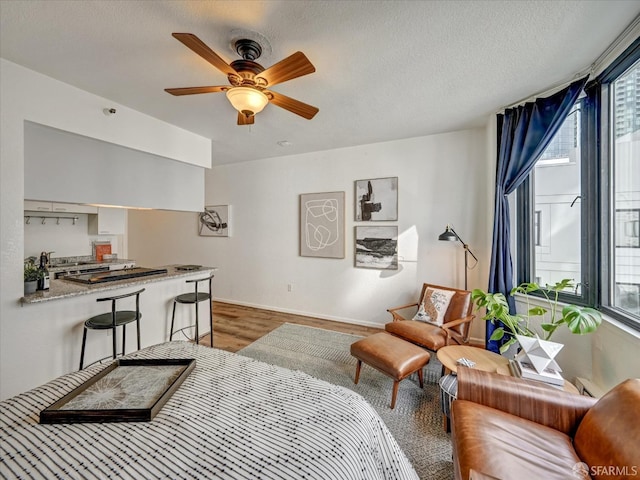 living room featuring ceiling fan, wood-type flooring, and a textured ceiling