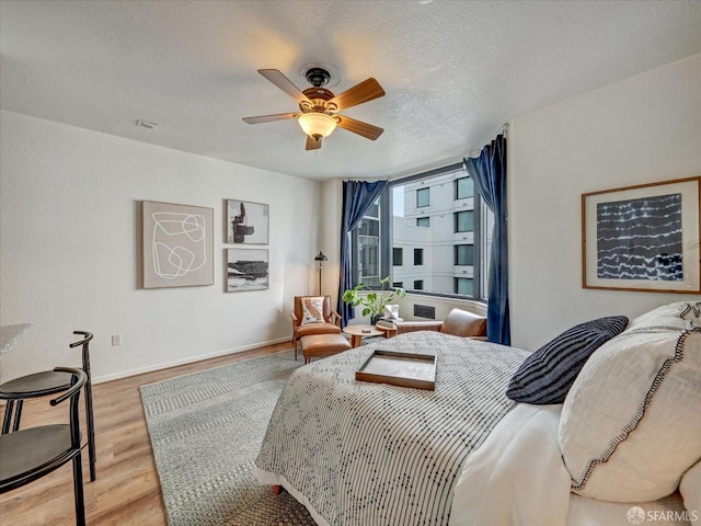 bedroom featuring a textured ceiling, light hardwood / wood-style floors, and ceiling fan