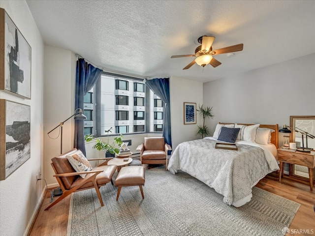 bedroom with hardwood / wood-style flooring, ceiling fan, and a textured ceiling