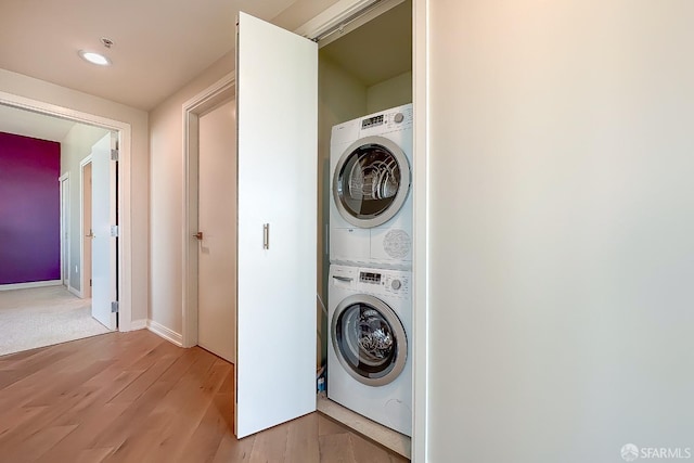 laundry room with stacked washing maching and dryer and light wood-type flooring