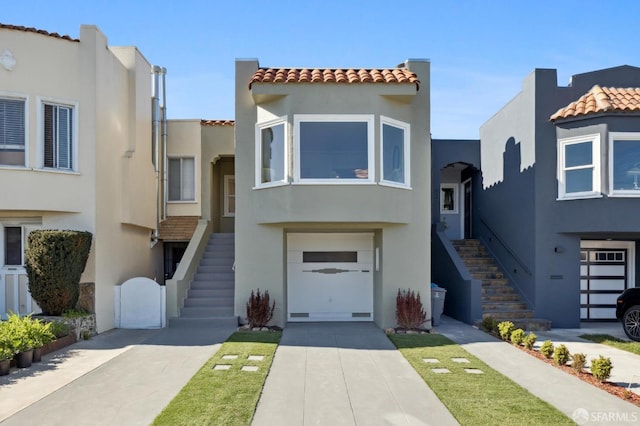 view of front of house featuring driveway, stairway, a tile roof, and stucco siding