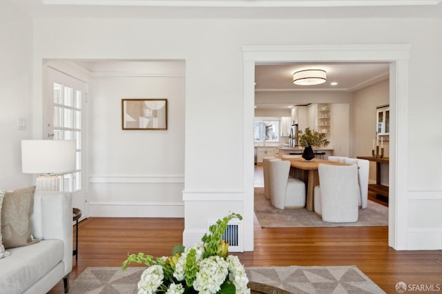 living area featuring visible vents, ornamental molding, and wood finished floors