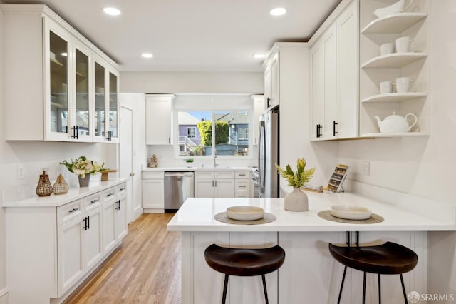 kitchen with a peninsula, open shelves, a breakfast bar area, and stainless steel appliances