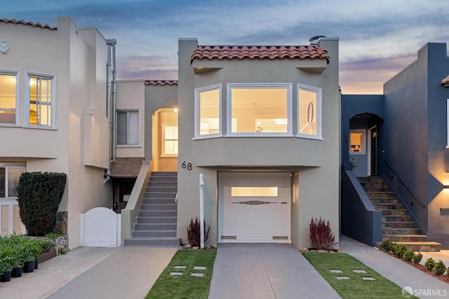 mediterranean / spanish house featuring stairs, a tiled roof, concrete driveway, and stucco siding