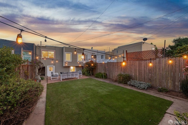 yard at dusk featuring a fenced backyard