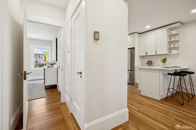 hall featuring recessed lighting, light wood-style flooring, and baseboards