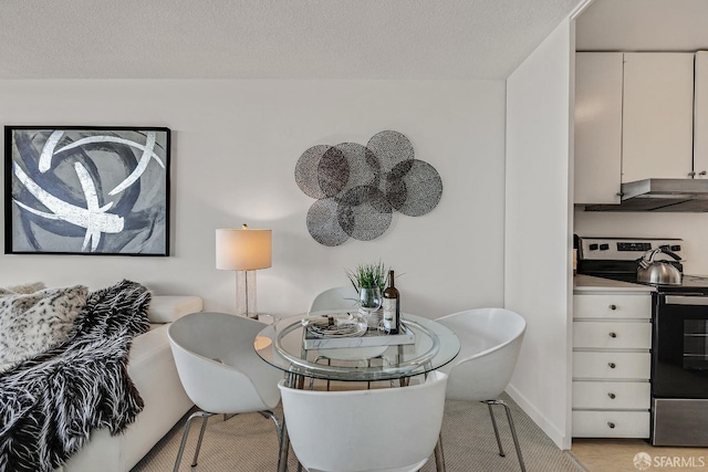 dining space with a textured ceiling and light wood-style flooring