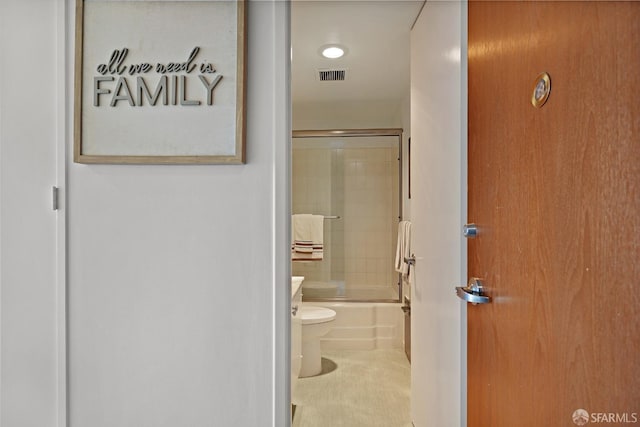 bathroom featuring toilet, enclosed tub / shower combo, and visible vents