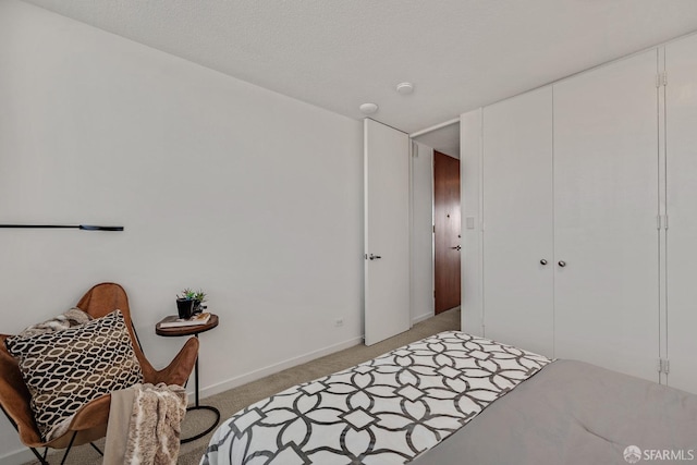 bedroom featuring light carpet, a closet, a textured ceiling, and baseboards