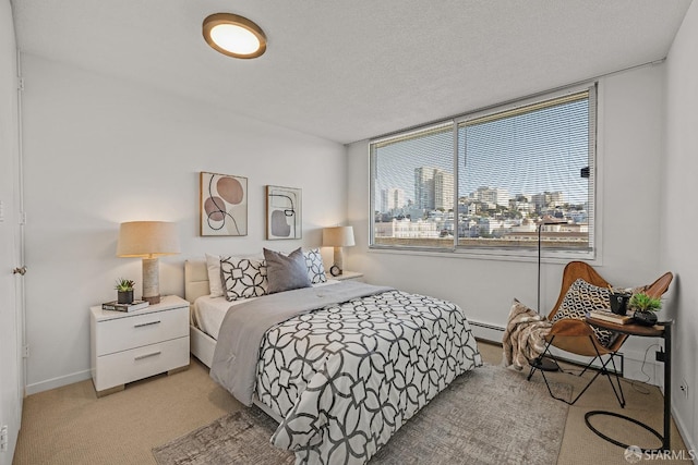 bedroom with a city view, light colored carpet, a baseboard heating unit, a textured ceiling, and baseboards