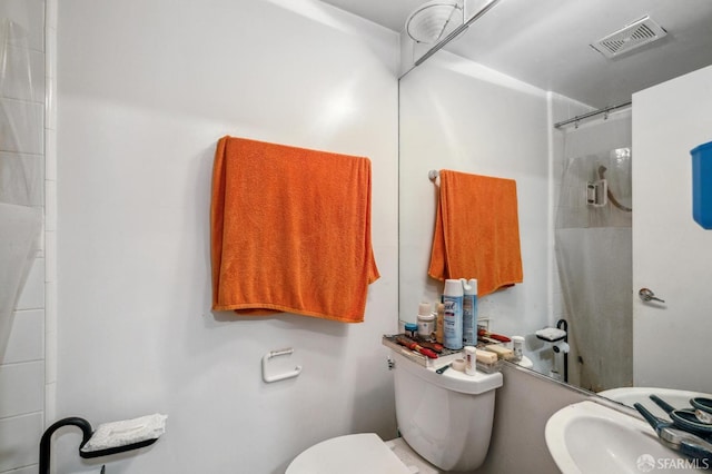 bathroom featuring a tile shower, sink, and toilet