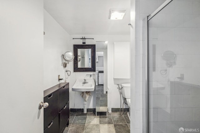 bathroom featuring sink, toilet, and a shower with door