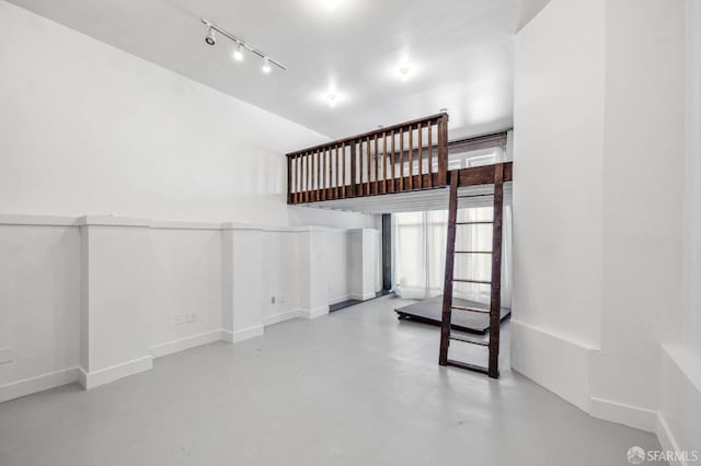 unfurnished living room featuring concrete flooring and rail lighting