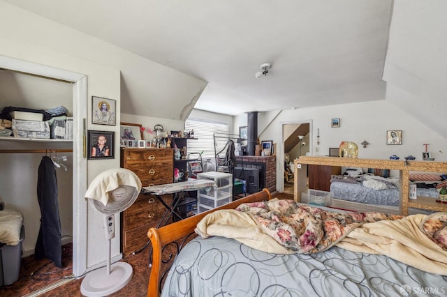 bedroom with a wood stove, vaulted ceiling, and hardwood / wood-style flooring