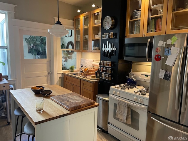 kitchen featuring a breakfast bar, sink, a center island, appliances with stainless steel finishes, and pendant lighting