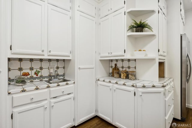 bar featuring dark wood-type flooring, sink, white cabinetry, stainless steel fridge, and decorative backsplash