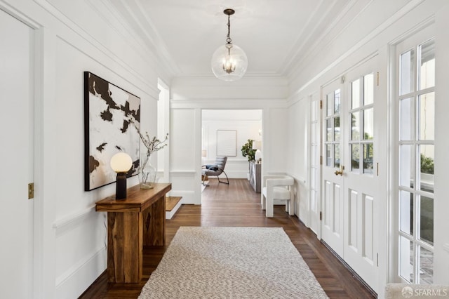 hall with crown molding, dark wood-type flooring, and an inviting chandelier