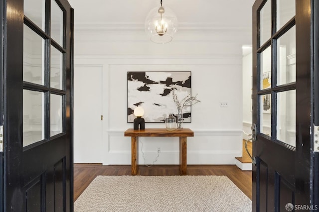 foyer with crown molding, dark hardwood / wood-style floors, and an inviting chandelier