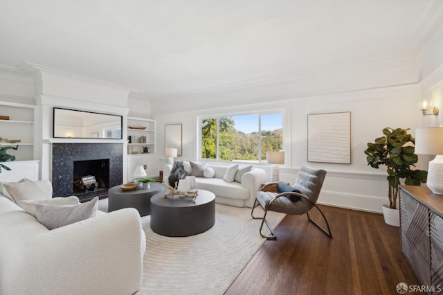 living room featuring dark wood-type flooring, ornamental molding, and a premium fireplace