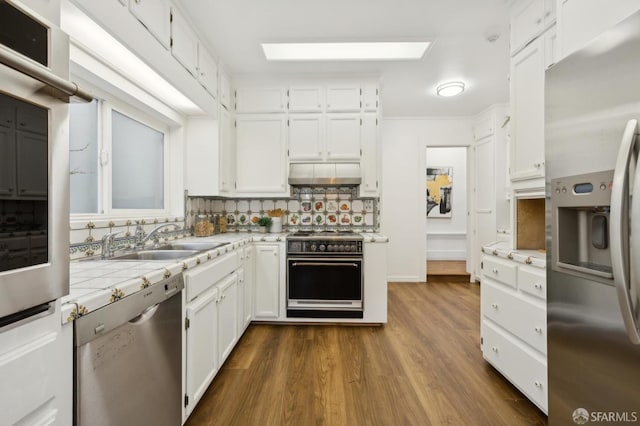 kitchen with ventilation hood, white cabinetry, sink, backsplash, and stainless steel appliances