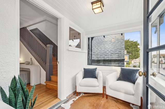 living area featuring wood finished floors, stairs, and a textured wall