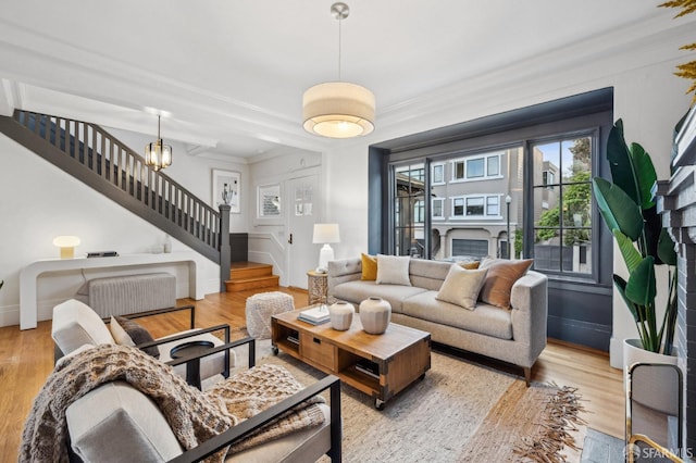 living room with stairs, wood finished floors, crown molding, and a fireplace