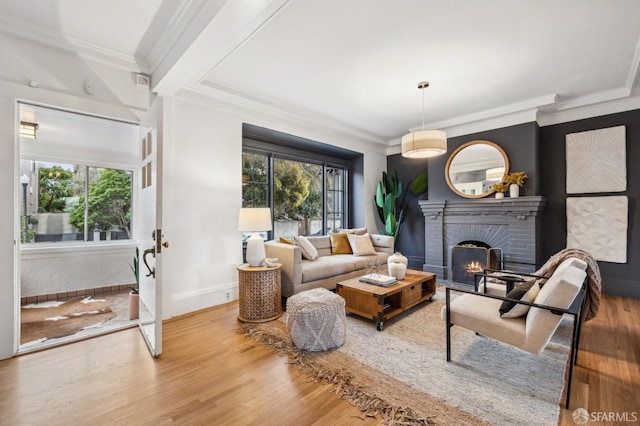 living room featuring baseboards, wood finished floors, a fireplace, and crown molding