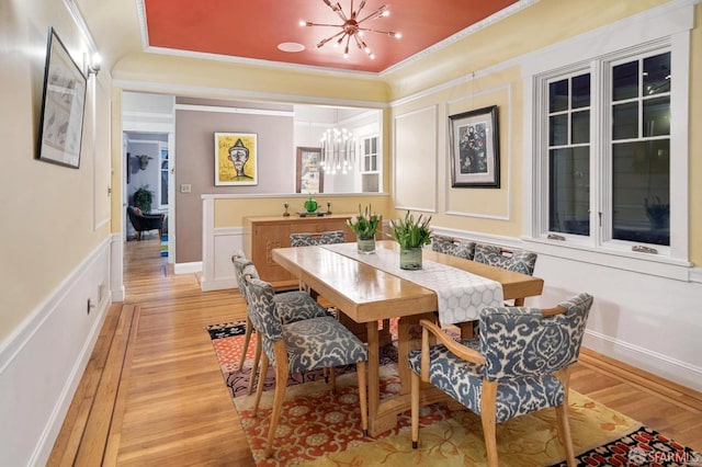 dining space featuring crown molding, baseboards, light wood-style floors, an inviting chandelier, and a raised ceiling