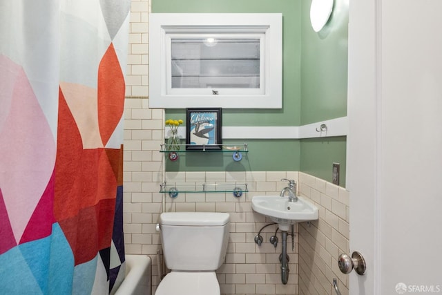 bathroom with a wainscoted wall, toilet, tile walls, and shower / tub combo