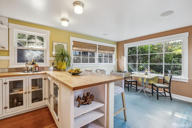 kitchen featuring butcher block countertops, a breakfast bar area, baseboards, and open shelves