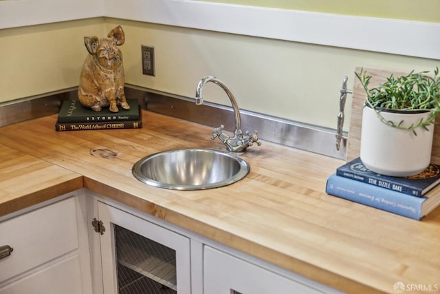 kitchen with a sink, white cabinetry, and butcher block countertops